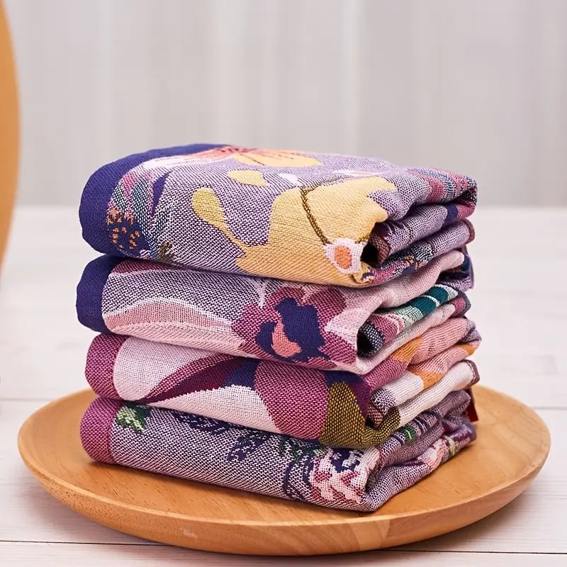Stack of folded floral towels on a wooden plate with a white background