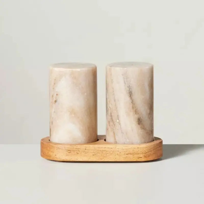 Marble salt and pepper shakers on a wooden stand against a light background