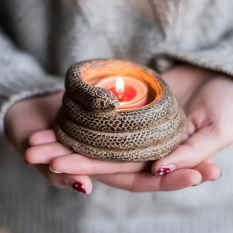 Person holding a snake-shaped candle holder with a lit candle inside.