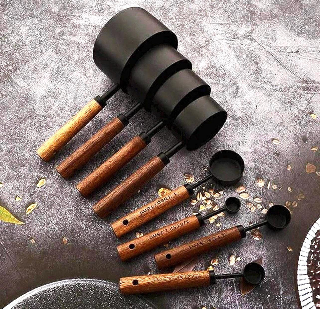 Set of black and wooden measuring cups on a textured surface
