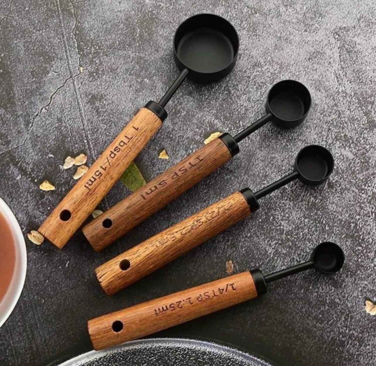 Set of wooden measuring spoons with black ends on a gray surface
